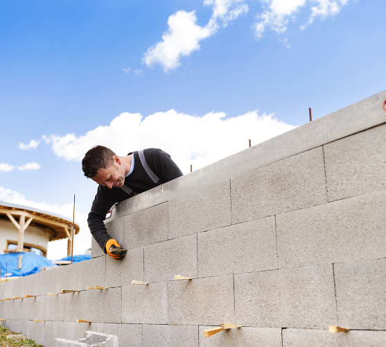 a man laying bricks at a construction site