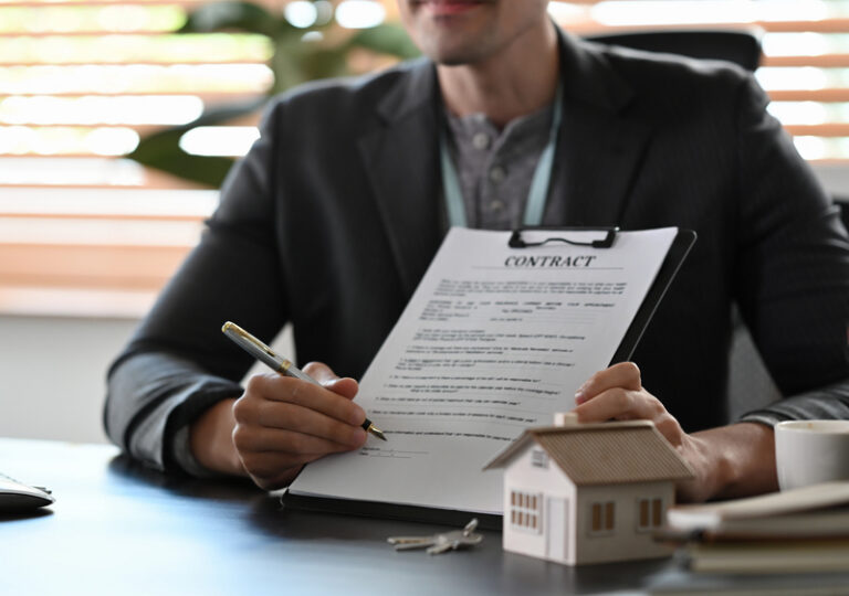 Man at desk holding a paper contract and a pen